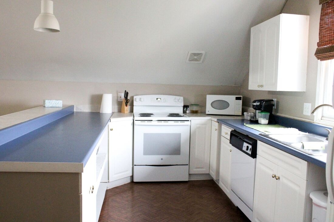 Kitchen in the Ranch Apartment with white cabinets and blue countertops